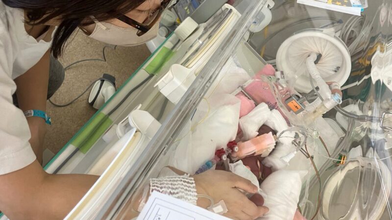 A mother touching her premature baby in an incubator in the NICU
